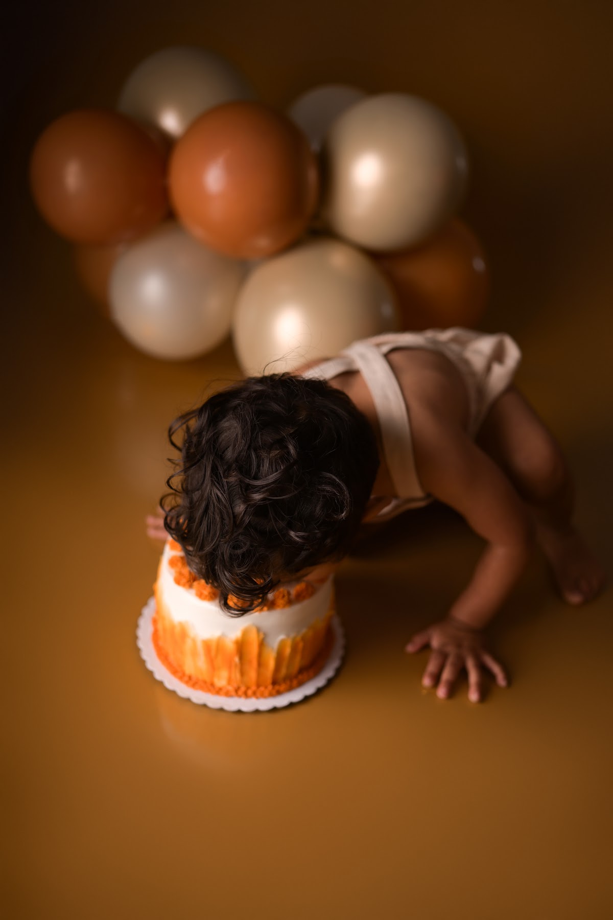 A toddler diving face-first into an orange cake-smash cake