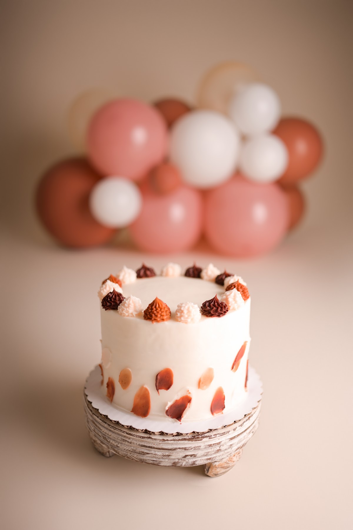 A terracotta and cream cake-smash cake with a matching balloon garland