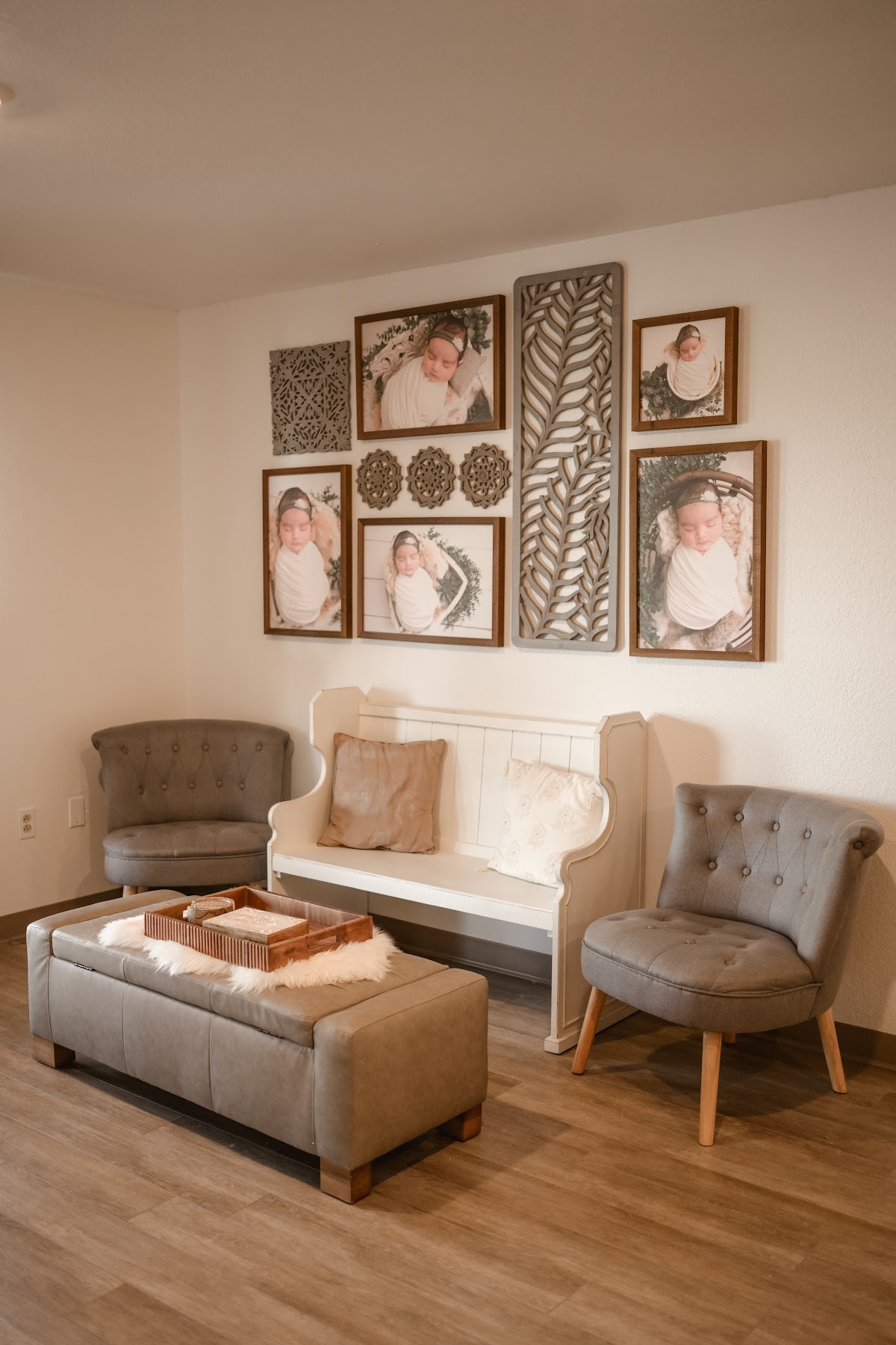 The studio interior with a gallery wall of framed newborn portraits, a bench and soft seating
